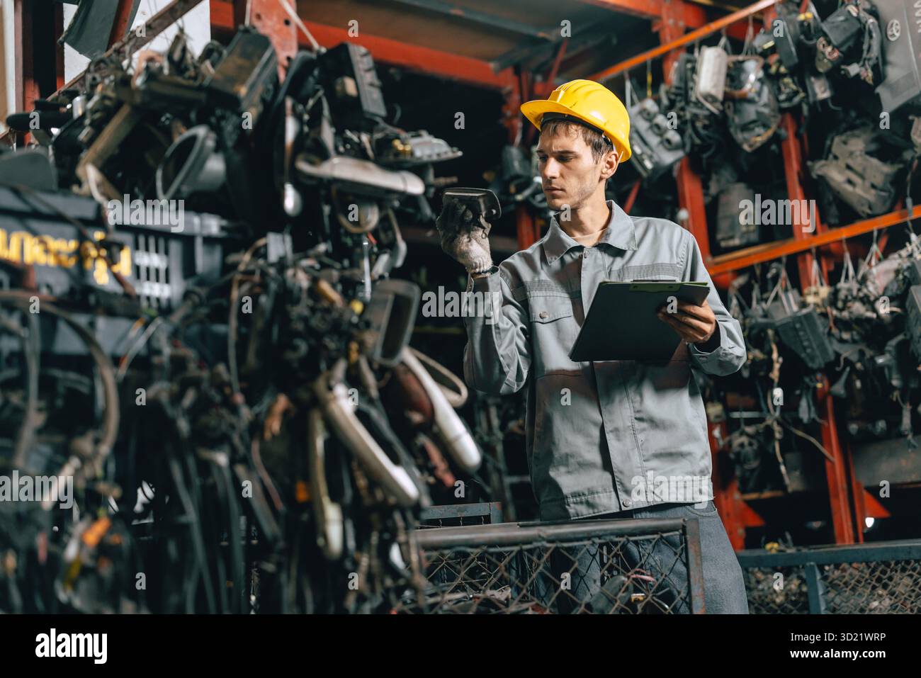 Technicien ouvrier masculin travaillant dans l'entrepôt d'atelier de vieil atelier de pièces de voiture de cour de ferraille de garage Banque D'Images