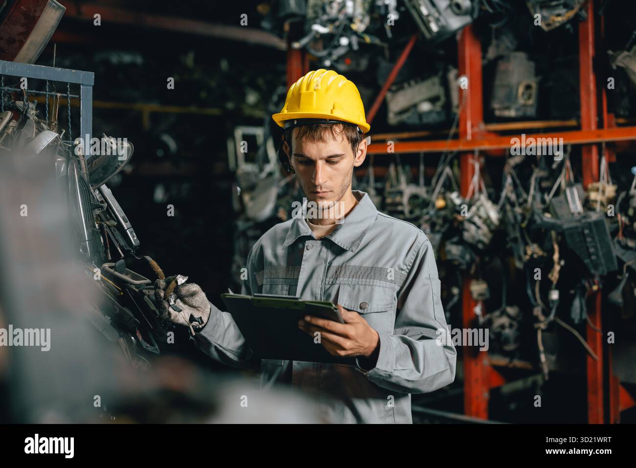 Technicien ouvrier masculin travaillant dans l'entrepôt d'atelier de vieil atelier de pièces de voiture de cour de ferraille de garage Banque D'Images