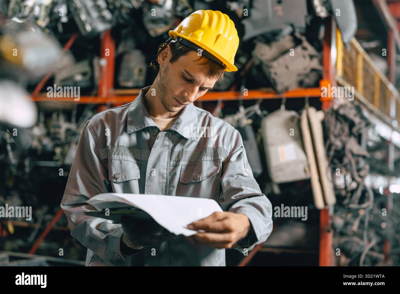 Technicien ouvrier masculin travaillant dans l'entrepôt d'atelier de vieil atelier de pièces de voiture de cour de ferraille de garage Banque D'Images