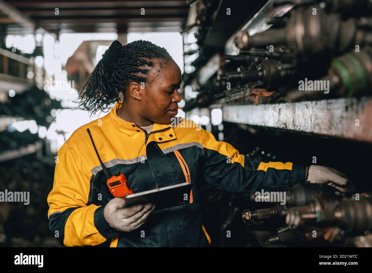 Travailleuse africaine du personnel d'ingénieur noire travaillant dans l'ancien entrepôt de stock de pièces de machines métalliques usagées. Banque D'Images