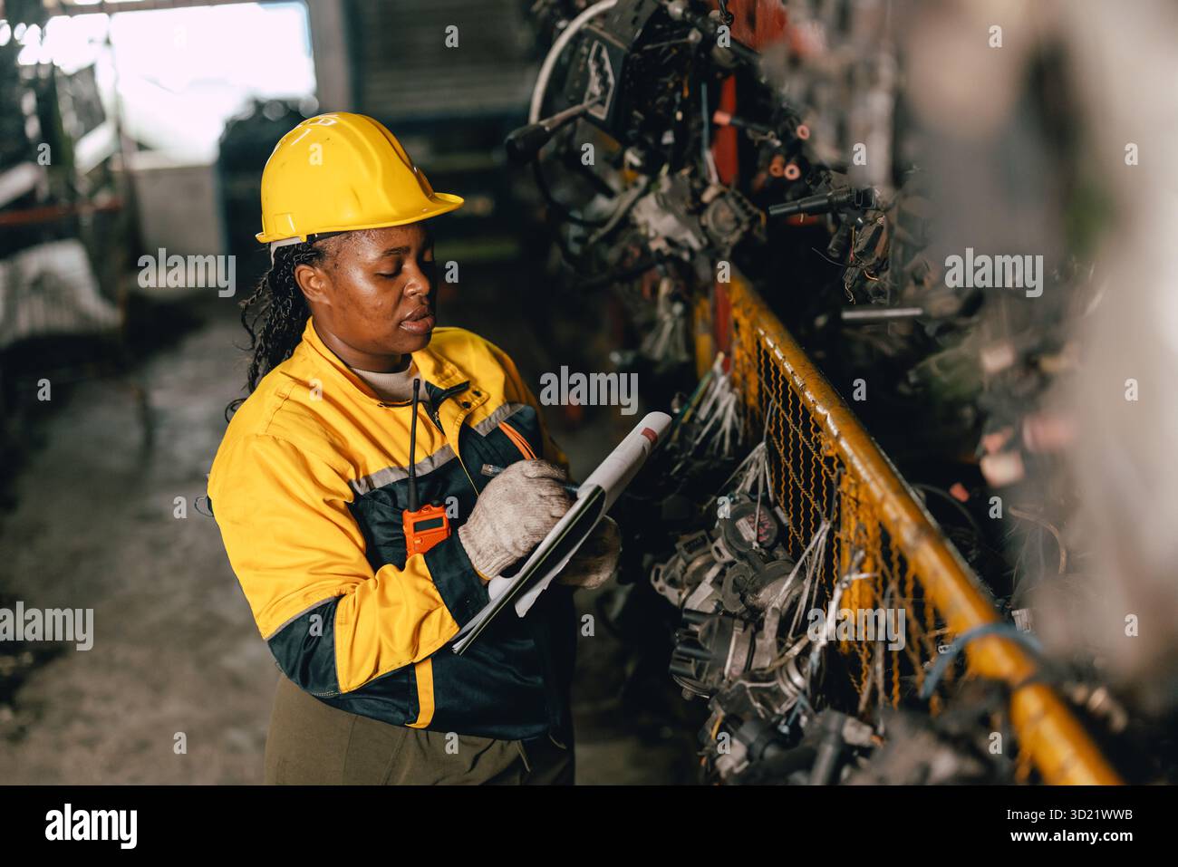 Travailleuse africaine du personnel d'ingénieur noire travaillant dans l'ancien entrepôt de stock de pièces de machines métalliques usagées. Banque D'Images