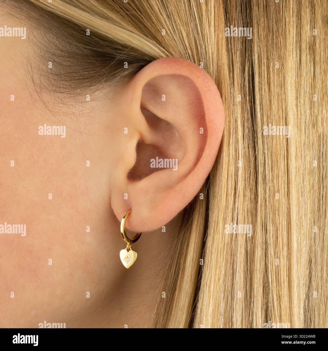 Boucle d'oreille coeur en or élégante sur l'oreille de la jeune femme caucasienne Banque D'Images