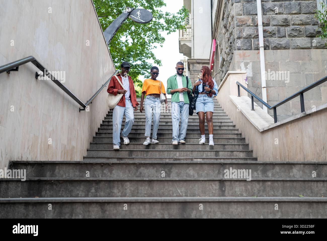 Groupe d'amis afro-américains réfléchis discutent avec enthousiasme de divers sujets, marchent à l'extérieur Banque D'Images
