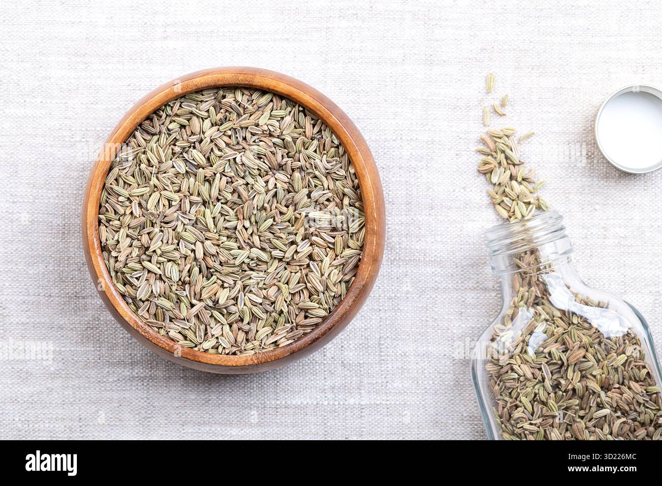 Graines de fenouil, dans un bol en bois, sur lin. Appelés à tort graines, les fruits de fenouil sont utilisés comme épices alimentaires, utilisés en cuisine, avec un goût anis. Banque D'Images