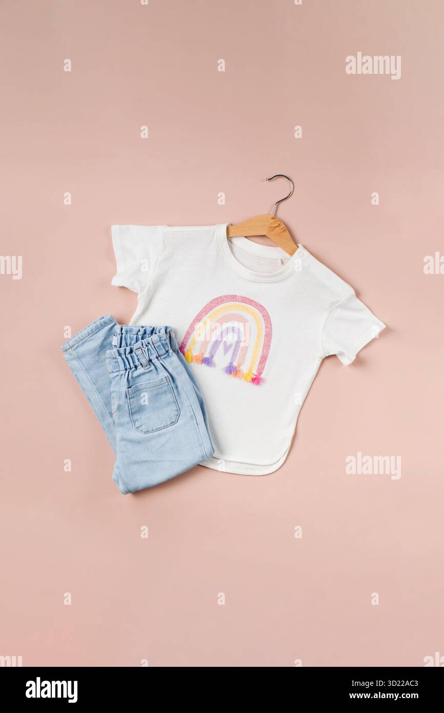 T-shirt pour enfants avec un Jean en arc-en-ciel et replié sur fond rose. Image de mode pour enfants. Banque D'Images