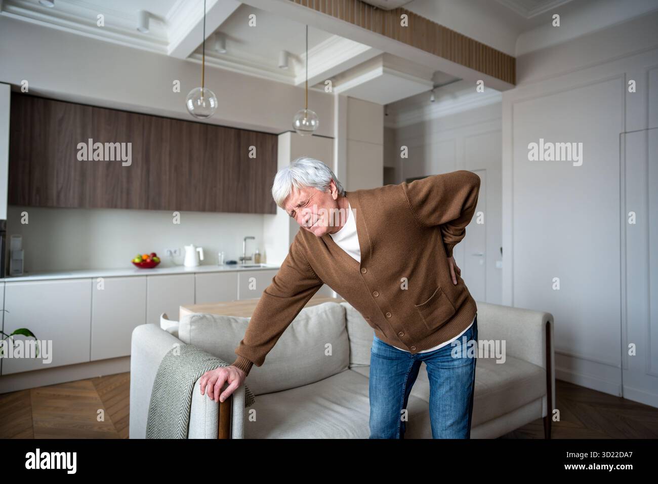 Plisser l'homme âgé souffre seul saisissant la colonne vertébrale douloureuse avec une mobilité limitée dans la maison vide Banque D'Images