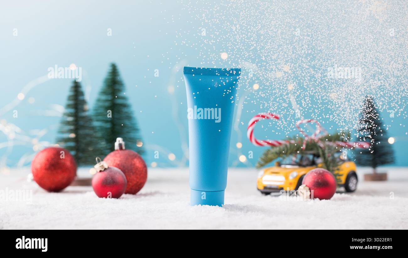 Maquette d'un tube bleu avec un produit cosmétique sur un fond de Noël avec de la neige qui tombe.Cadeau pour la nouvelle année. Banque D'Images