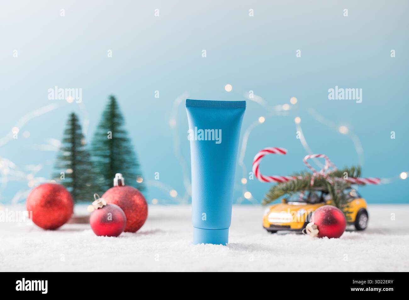 Maquette d'un tube bleu avec un produit cosmétique sur fond de Noël.Cadeau pour la nouvelle année. Banque D'Images