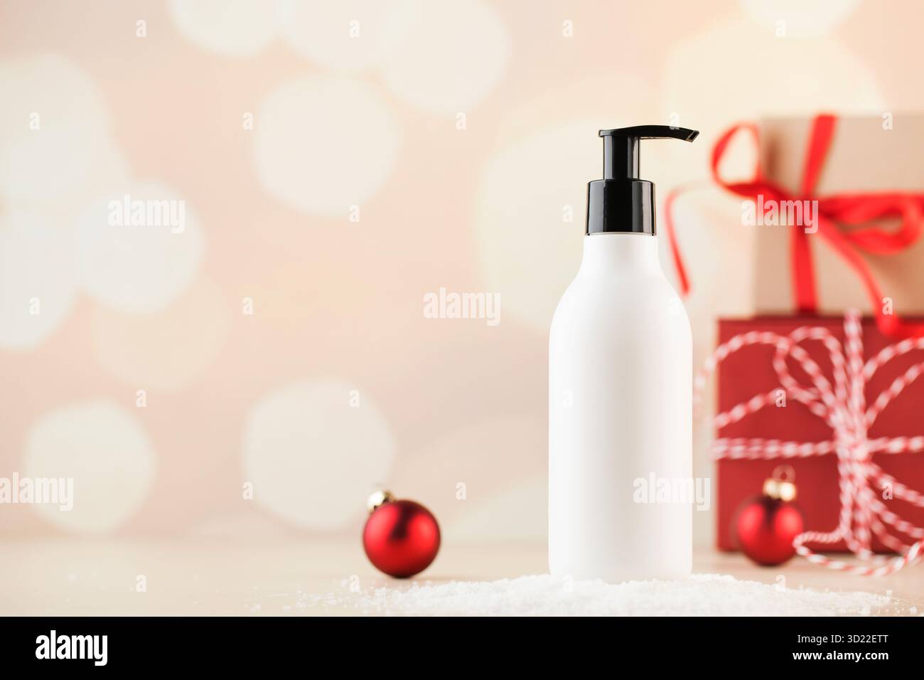 Maquette d'un distributeur blanc avec un produit cosmétique sur la neige sur fond de cadeaux de Noël. Banque D'Images