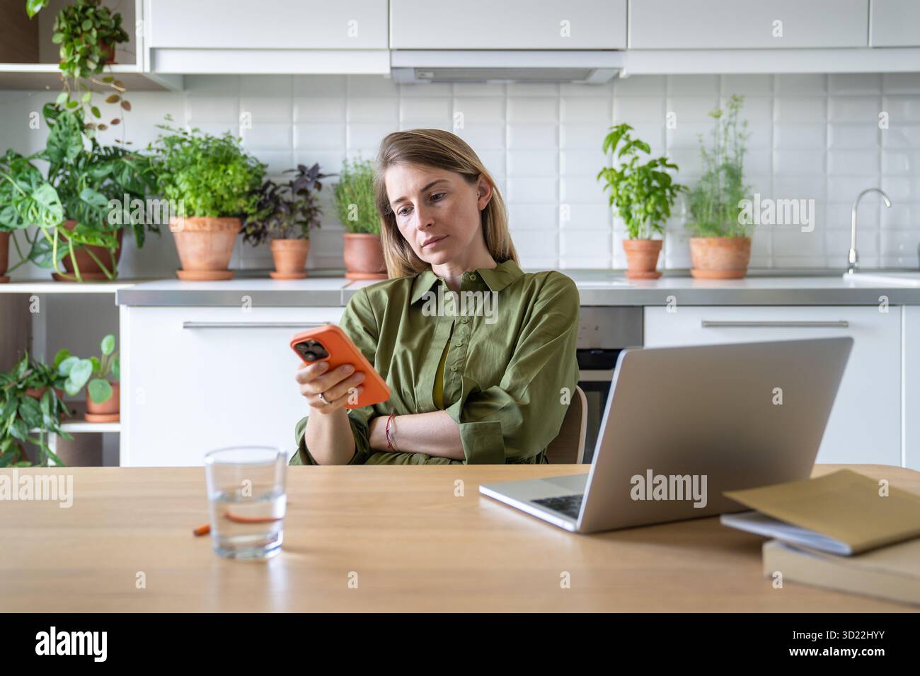 Téléphone de défilement de femme agitée, prenant le travail d'ordinateur portable pause à la maison. Navigation Internet non ciblée, discussion Banque D'Images