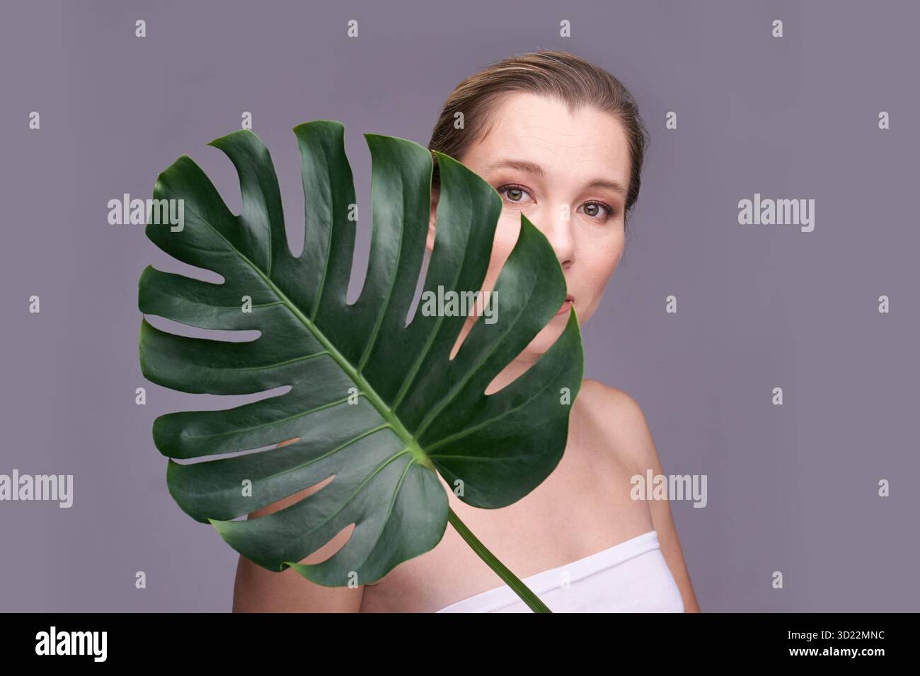 Femme adulte caucasienne avec feuille de monstera, beauté naturelle et concept de soins de la peau Banque D'Images