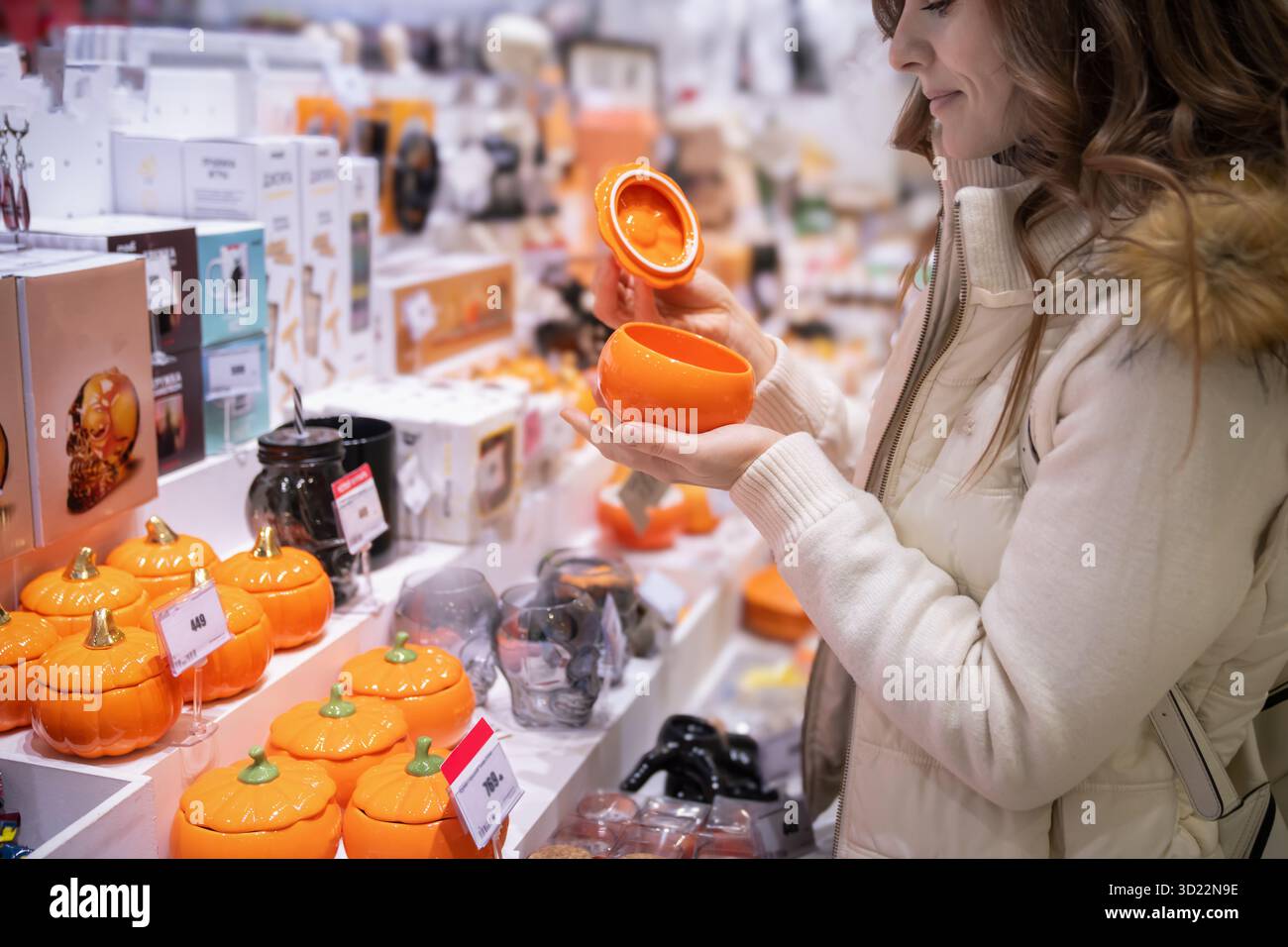 À la veille d'Halloween, une femme parcourt un marché local, sélectionnant des citrouilles en céramique colorées et des pots uniques pour la décoration intérieure. Elle aime la fête Banque D'Images