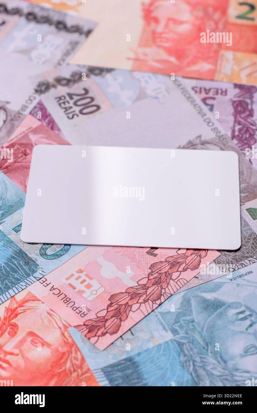 La carte en plastique blanche comme symbole des paiements sans espèces sur le fond de papier-monnaie du Brésil Banque D'Images