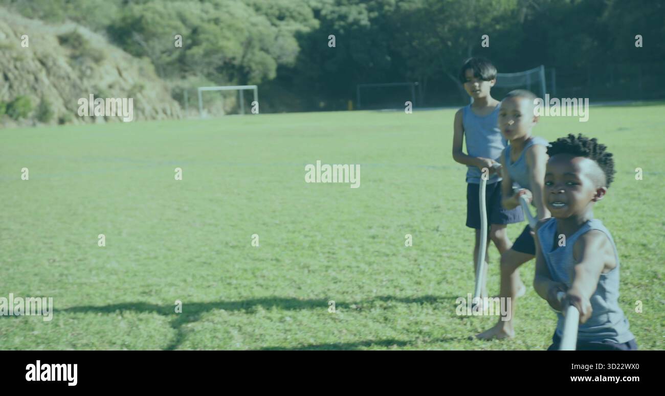 Trois amis jouant au remorqueur de la guerre avec une longue corde sur un terrain de football en herbe près des poteaux de but, espace de copie Banque D'Images