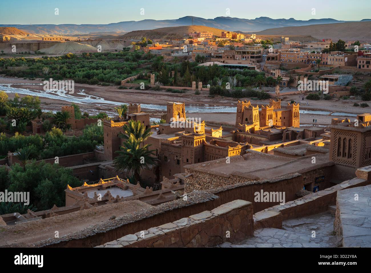 Ancienne ville désertique avec des bâtiments en argile sous un ciel clair et oasis verte environnante. Ait Benhaddou. Maroc Banque D'Images