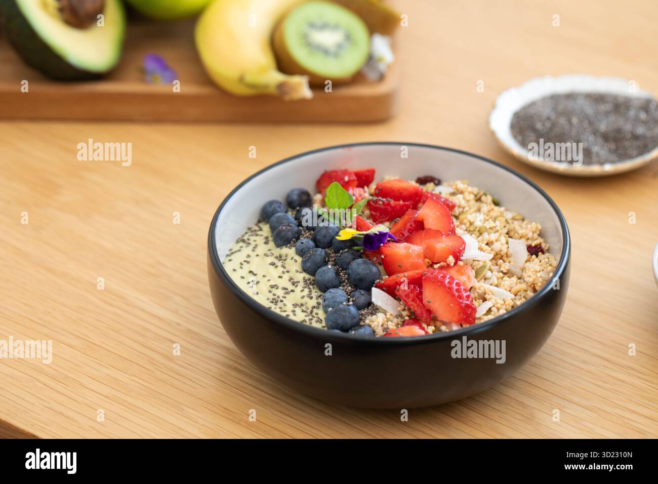 Bol de smoothie d'avocat de petit déjeuner sain avec des fruits frais et des graines de chia sur une table en bois Banque D'Images