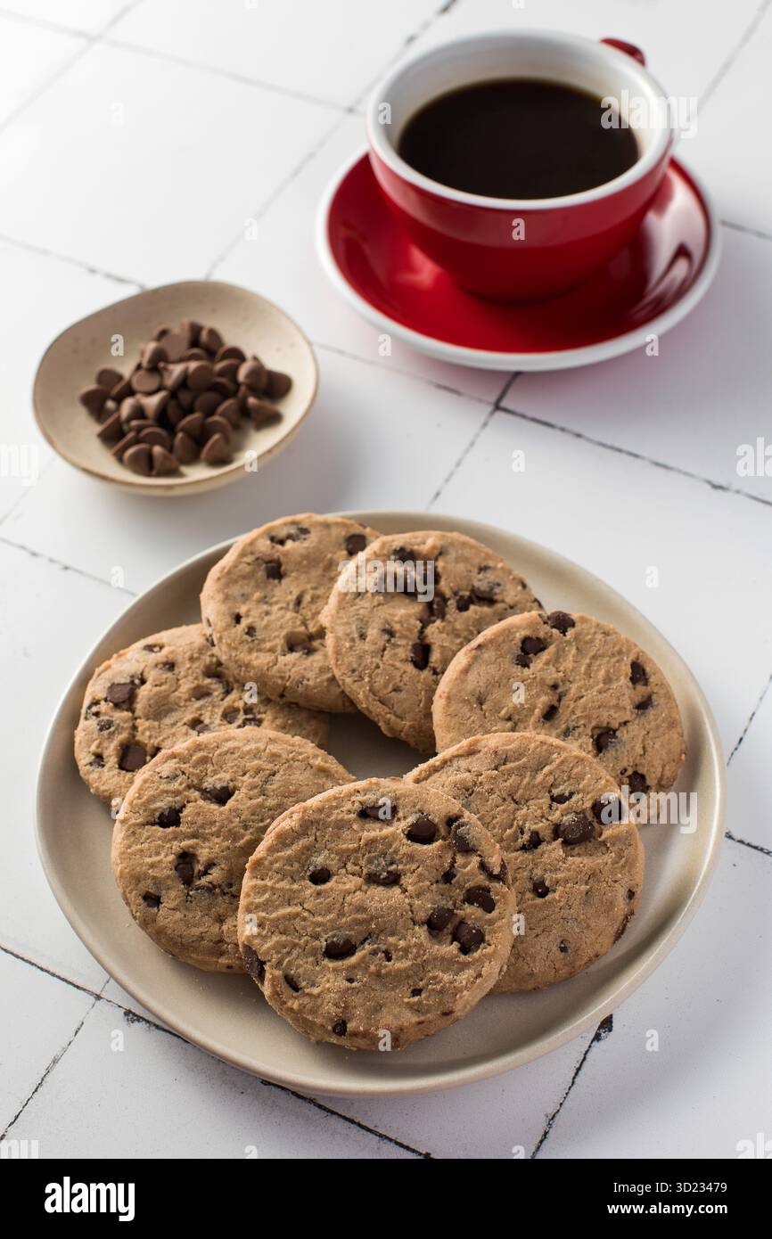 Délicieux biscuits aux pépites de chocolat avec une tasse de café rouge. Petit déjeuner. Banque D'Images