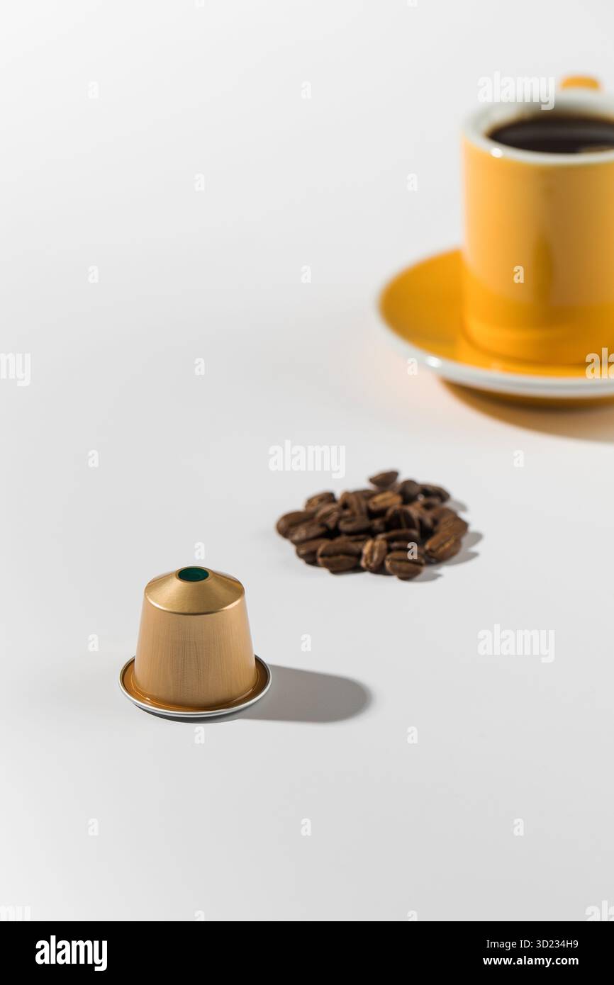 Capsule de café avec une tasse et une soucoupe en arrière-plan Banque D'Images