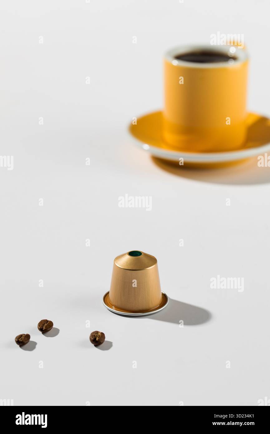 Capsule de café avec une tasse et une soucoupe en arrière-plan Banque D'Images