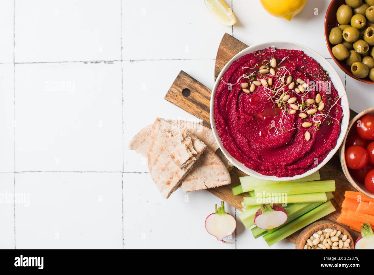 Houmous de betterave dans un bol sur une planche avec des légumes frais, céleri, carottes, pita. Copier l'espace Banque D'Images