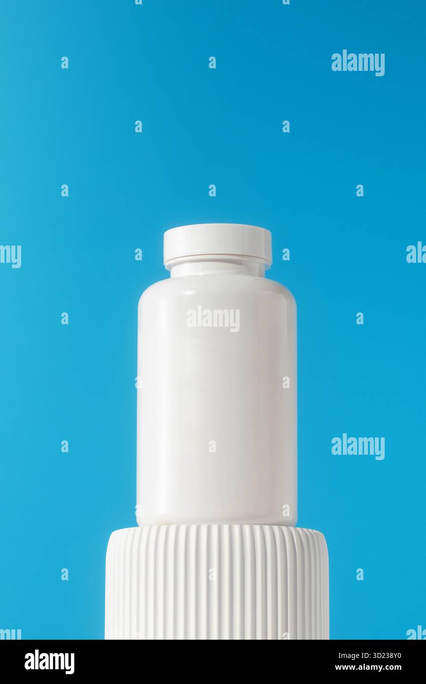Mockup est un pot blanc avec des pilules ou des vitamines sur un podium. Préparations médicales. Banque D'Images