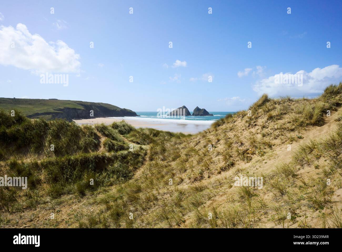 Holywell Bay and Beach, Cornwall, Royaume-Uni. Beau paysage côtier avec des dunes de sable et des îles rocheuses lointaines sous un ciel bleu clair. Banque D'Images