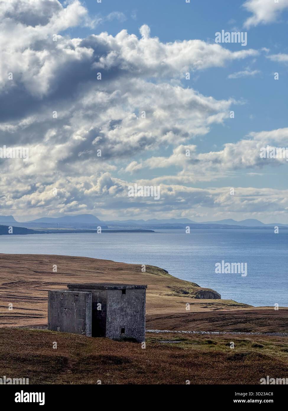 Bâtiment en pierre éloigné sur un paysage côtier sous un ciel dramatique avec des montagnes lointaines. Dunnet Head, Écosse Banque D'Images