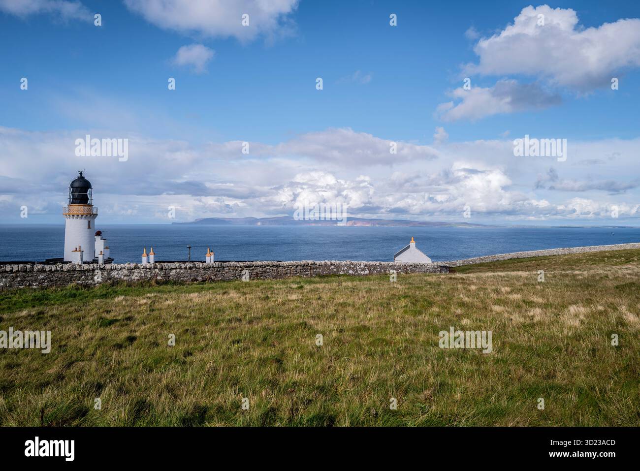 Phare et petite maison sur falaise herbeuse surplombant l'océan sous un ciel partiellement nuageux. Dunnet Head, Écosse Banque D'Images