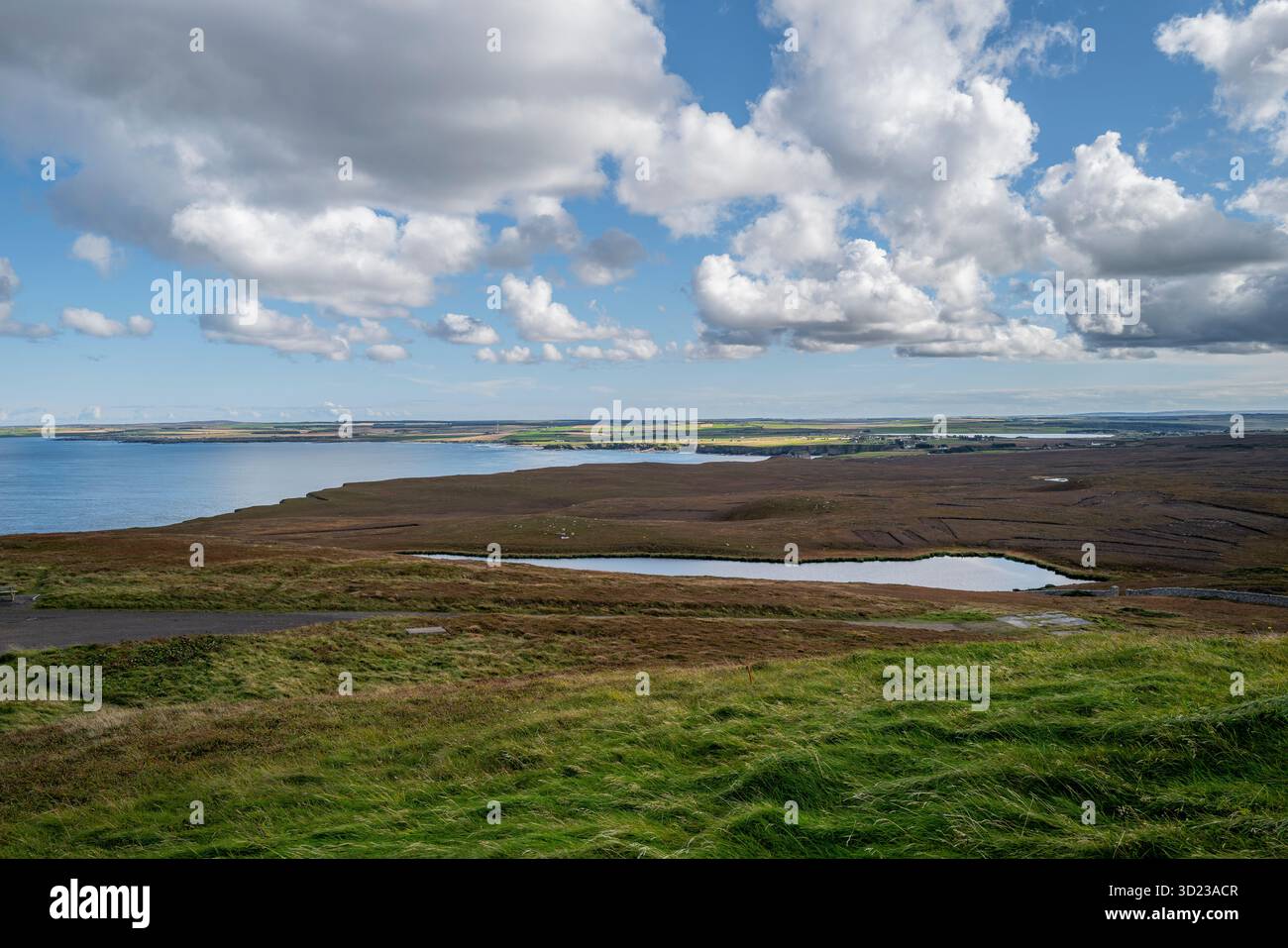 Un vaste paysage avec des champs verts, des eaux lointaines et un ciel bleu nuageux. Dunnet Head, Écosse Banque D'Images