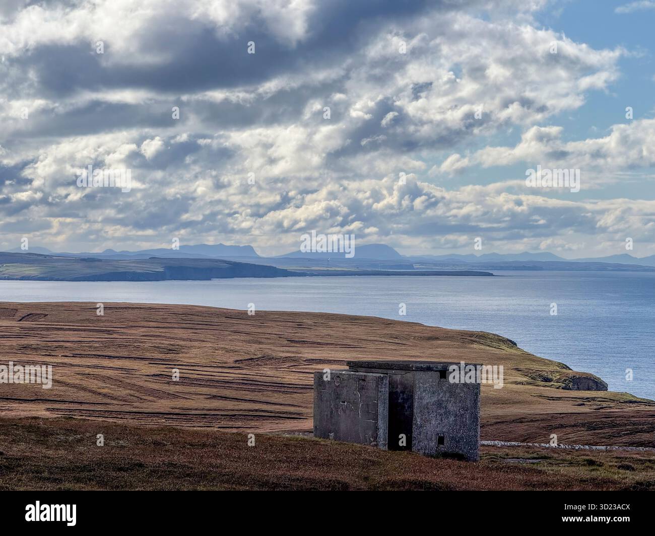 Un bâtiment en pierre solitaire se trouve sur un vaste paysage côtier accidenté sous un ciel parsemé de nuages. Dunnet Head, Écosse Banque D'Images