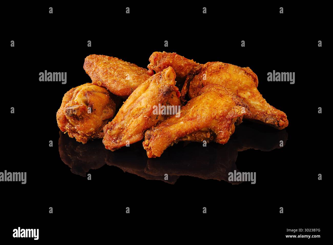 Ailes de poulet frites croustillantes disposées sur une surface réfléchissante sombre Banque D'Images