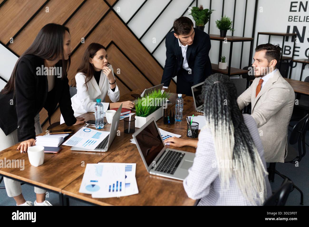 Équipe marketing. Groupe de jeunes gens modernes en vêtements décontractés et élégants discutant quelque chose pendant qu'ils travaillent dans le bureau créatif Banque D'Images