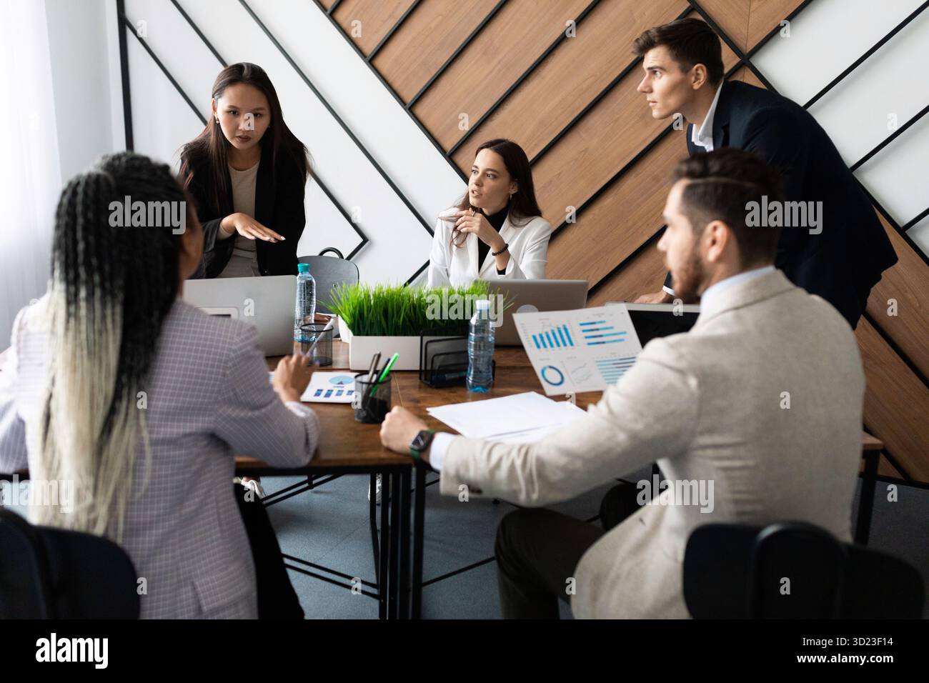 Équipe marketing. Groupe de jeunes gens modernes en vêtements décontractés et élégants discutant quelque chose pendant qu'ils travaillent dans le bureau créatif Banque D'Images