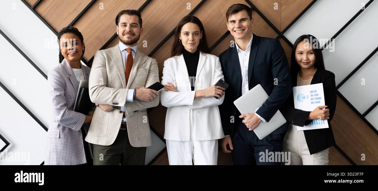 Personnel hétérosexuel multi-national de bureau avec un sourire regardant la caméra debout contre le mur Banque D'Images