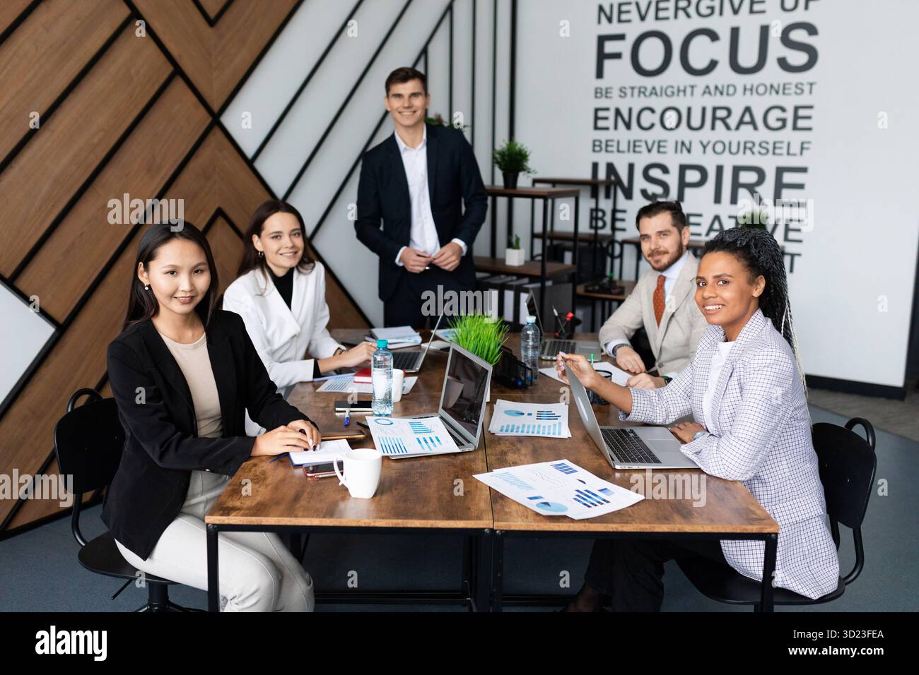 Les collègues au bureau assis sur une grande table de travail regardent la caméra Banque D'Images