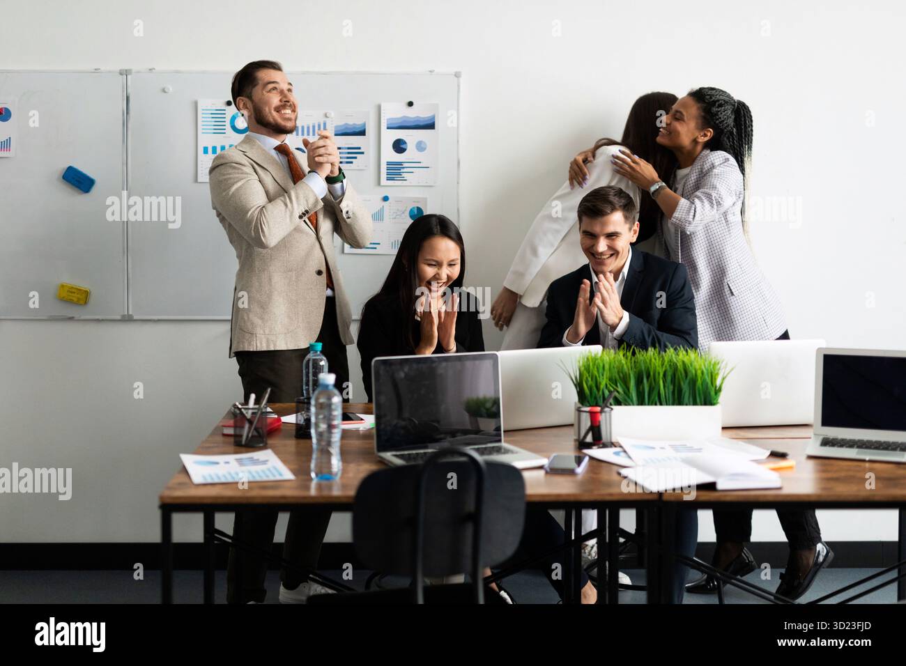 Une équipe d'employés de bureau tout en se réjouissant tout en regardant un écran d'ordinateur portable Banque D'Images