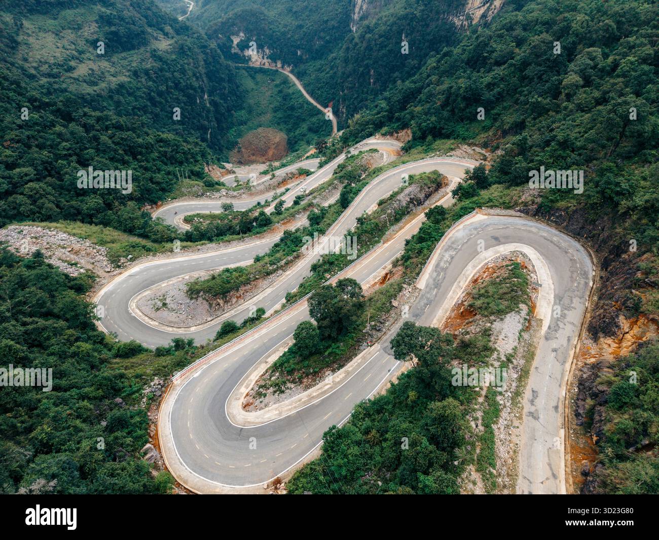 Vue aérienne d'une route de montagne sinueuse entourée de forêts verdoyantes et de collines escarpées. Col de montagne Khau Coc Cha, Bao Lac, Cao Bang, Vietnam Banque D'Images