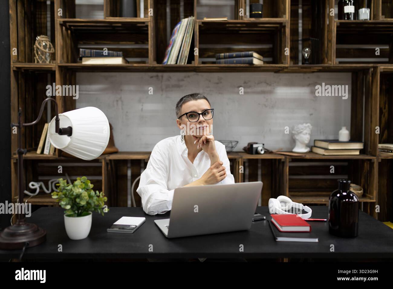 Élégante femme européenne caucasienne dans le lieu de travail dans des lunettes derrière un ordinateur portable Banque D'Images