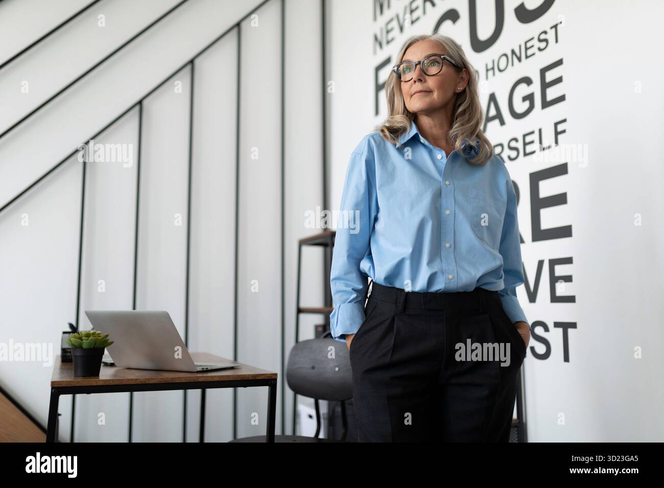 Portrait en gros plan d'une dirigeante forte âgée de 50 ans assise sur une chaise avec pour toile de fond un bureau moderne. Affaires dans Banque D'Images