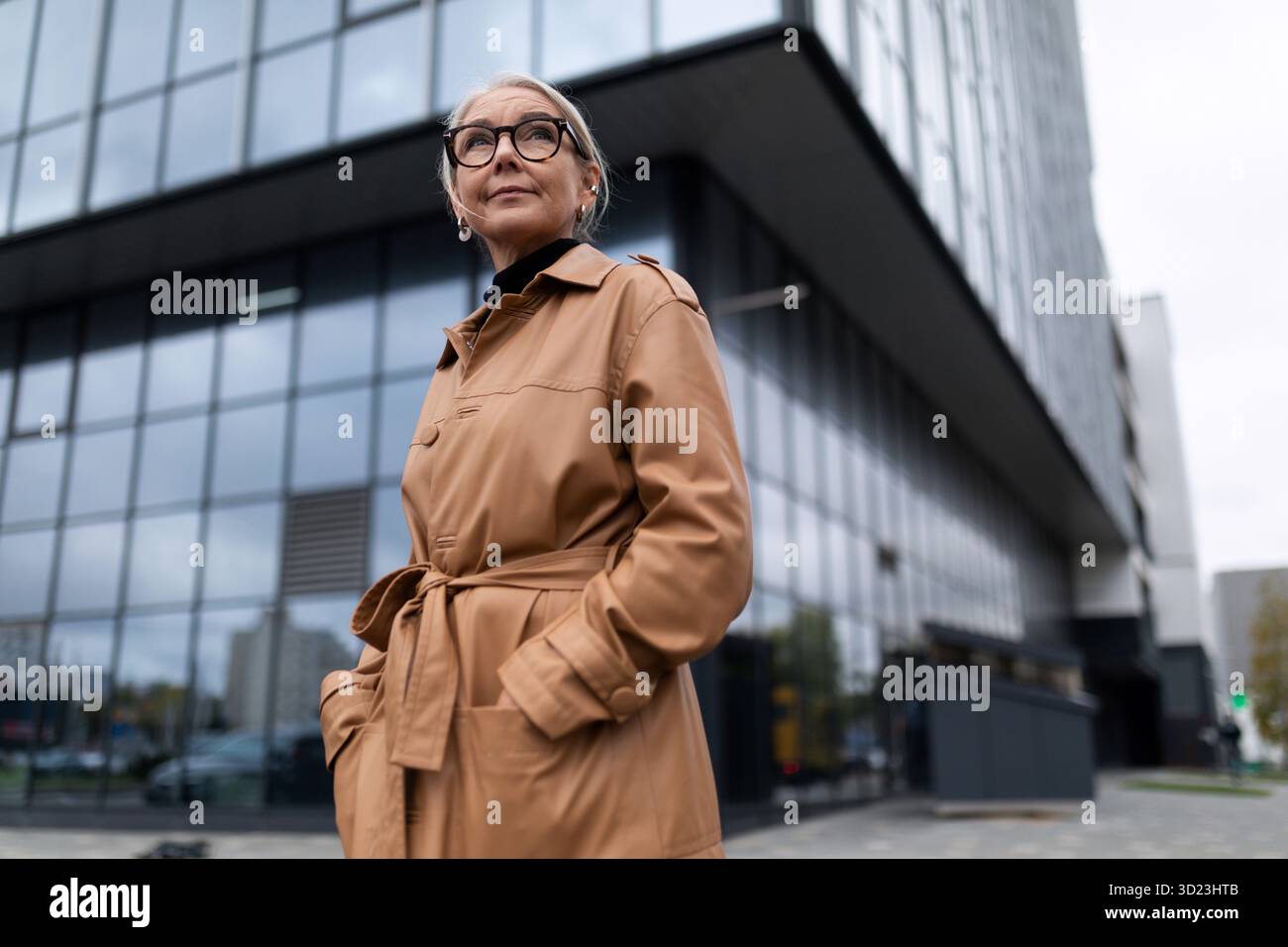 Femme âgée réussie tête sur le fond de la façade d'un immeuble de bureaux moderne Banque D'Images