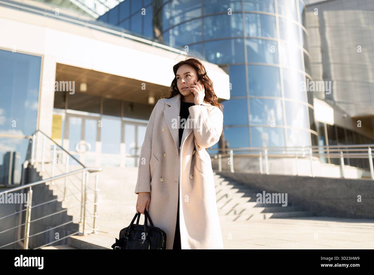Portrait d'une femme d'affaires prospère gestionnaire de 35 ans parlant sur un téléphone portable sur le fond de l'entrée à Banque D'Images
