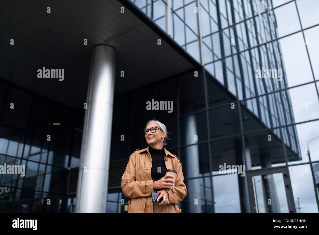 Femme d'affaires de 50 ans sur fond d'un énorme gratte-ciel de bureau Banque D'Images
