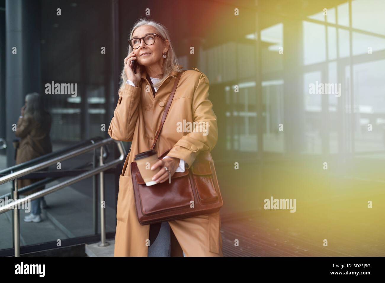 Femme élégante âgée parlant sur le téléphone portable à côté du centre commercial Banque D'Images