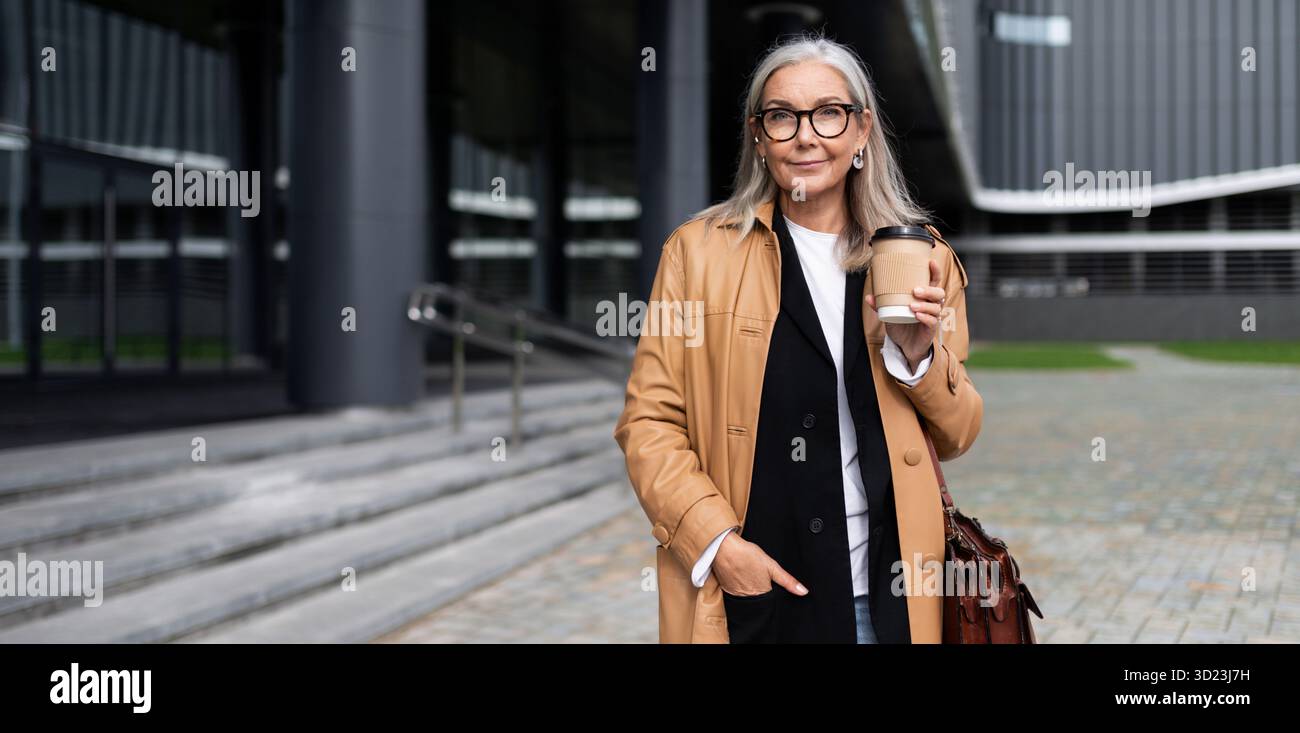 Femme caucasienne mature avec une tasse de café dans ses mains sur le fond du centre commercial Banque D'Images