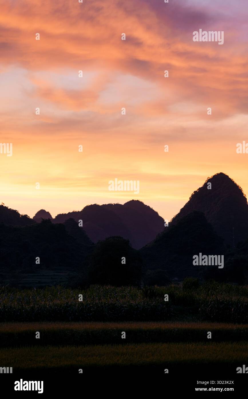 Superbe coucher de soleil sur des silhouettes de montagne lointaines avec un ciel vibrant. Phong Nam, tr˘ng KH·nh District, Cao Bang, Vietnam Banque D'Images