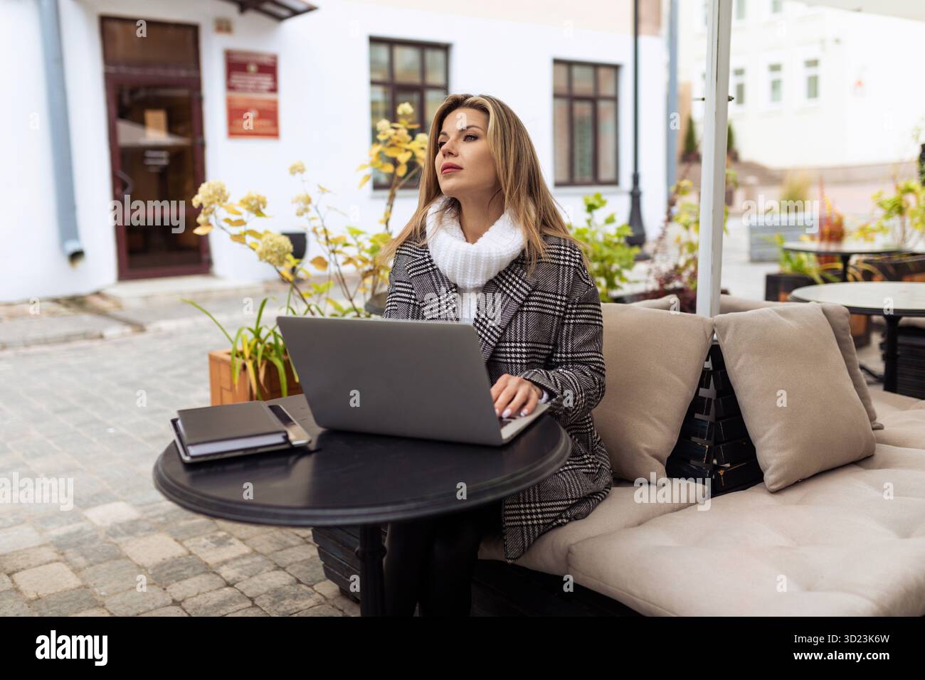 Femme d'affaires adulte travaillant sur un ordinateur portable à une table dans un café de la ville Banque D'Images
