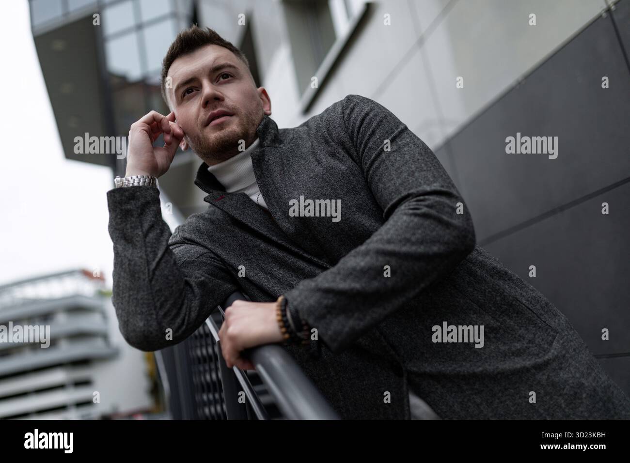 Portrait d'un homme d'âge moyen élégant et brutal sur le fond d'un mur de bâtiment gris Banque D'Images
