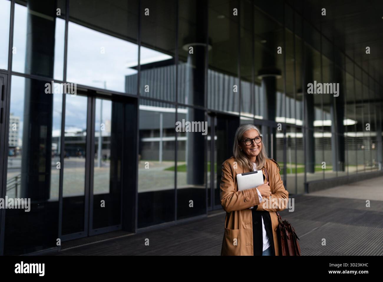 Femme d'affaires de cinquante ans avec une tablette dans les mains à l'entrée du centre d'affaires Banque D'Images