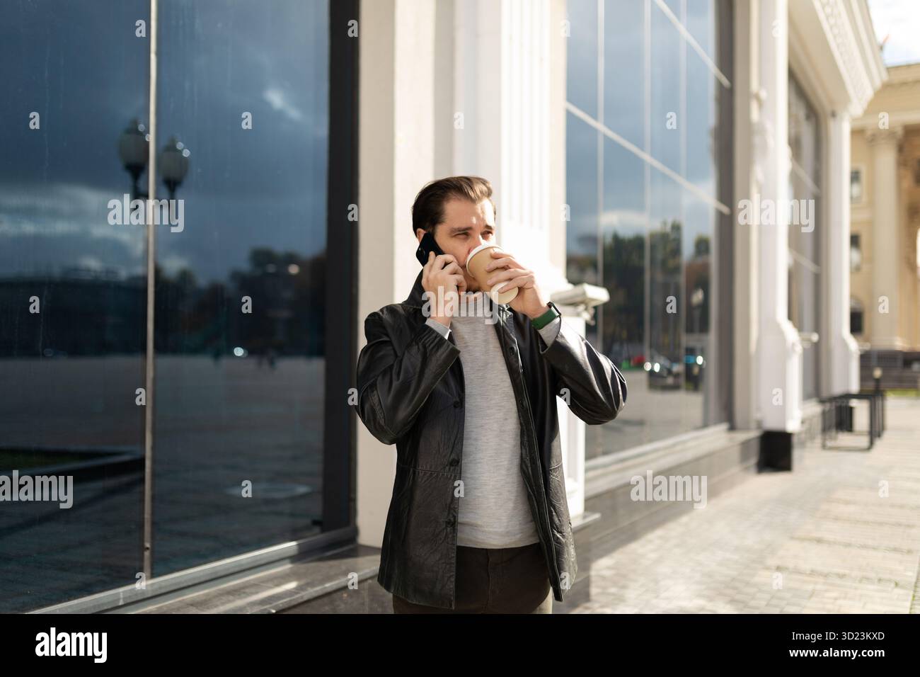 homme de 35 ans parlant au téléphone tout en buvant du café en ville Banque D'Images