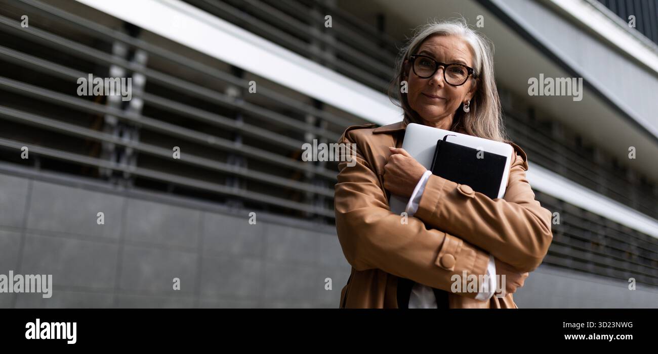 Portrait d'une femme d'affaires mature d'affaires réussie avec un ordinateur portable dans ses mains à l'extérieur du bureau Banque D'Images